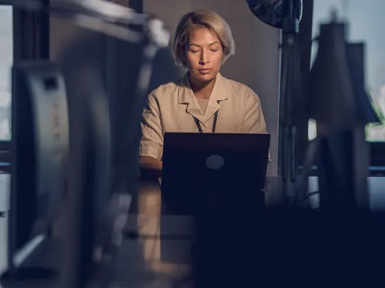 A copywriter writing outreach on a laptop in a dark office